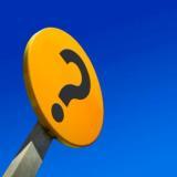 black question mark on round yellow sign against blue sky